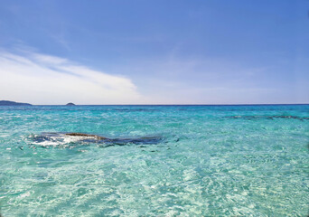 turquoise sea with small waves, coastline, blue tropical sky with white cloud.