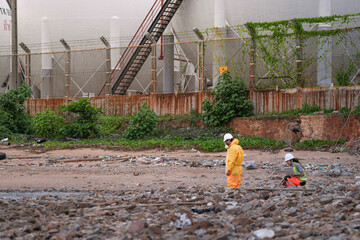 Environmental field team in protective gear analyzes water samples on a polluted beach. One holds a...