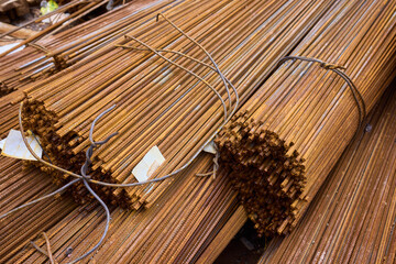 Stacked steel rods are prominently observed at a bustling construction site in progress