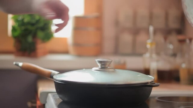 hand closes glass lid in which steak osso buco with vegetables is being fried. High quality 4k footage