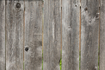 Weathered wooden fence with vertical planks. The texture shows natural aging, with knots and grain...
