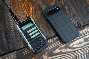 Two different types of communication: a portable two-way radio and a modern rugged smartphone on a...