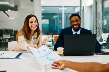 Business people having meeting exchanging documents and smiling at the office