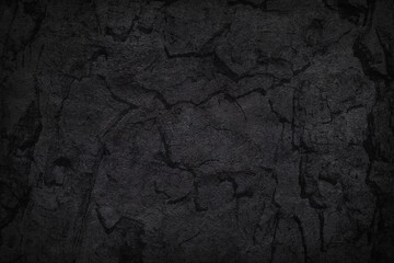 Texture of black concrete or tree bark background. Dark wallpaper with rough cement texture. Empty grunge wall concept or floor backdrop. Abstract surface mockup. Top view, close up, copy space