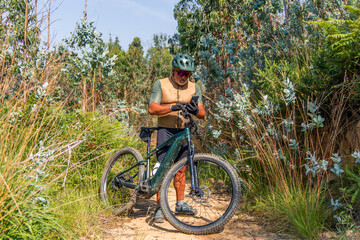 Senior cyclist using smartphone on electric mountain bike in nature