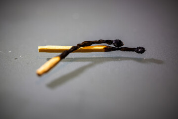 Artistic macro image of two burned matchsticks lying crossed on a reflective surface.