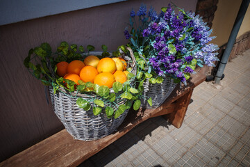 On a bench is a basket filled with lavender and oranges