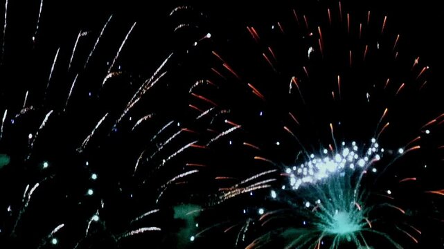 Against the inky canvas of night, vibrant fireworks explode in New York. Streaks of red and white dance with bursts of luminescent blue.