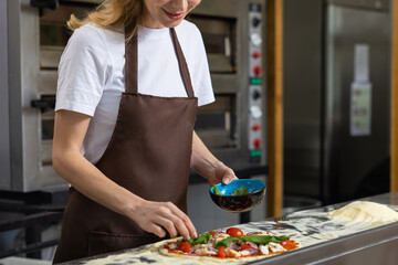 Woman preparing pizza in kitchen