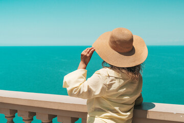 Woman in Summer Hat Looking at Sea Horizon from Cliff