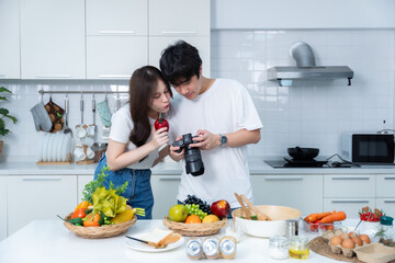 Happy portrait of loving young asian of having fun standing Take a photo after enjoy cook cooking with vegetables, meat, bread while standing on a kitchen Condo life or home