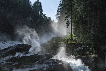 Majestic Krimml waterfall cascades through rocks and mist in Austria's scenic landscape during morning light