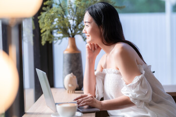 Asian freelance people business female talking making using casual working with laptop computer and coffee at home in the living room indoors artificial rose bouquet of red and pink roses rose vase