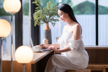 Asian freelance people business female talking making using casual working with laptop computer and coffee at home in the living room indoors artificial rose bouquet of red and pink roses rose vase
