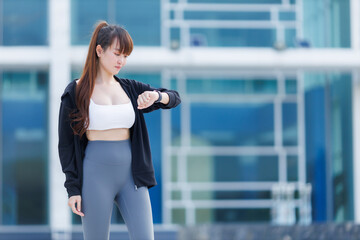 Portrait of beautiful asian Young woman in Black robe sportswear working out outside. training on public equipment Watching the Smart Watch in outdoor at park. concept Exercise Healthy lifestyle.