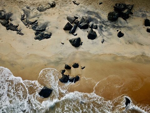 Black rock Liberian beach, above a high-angle drone view of the ocean washing the seashore rocks. Rocky sea coast of the North Atlantic Ocean.