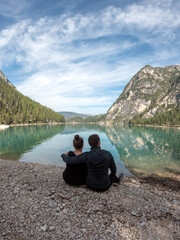 Couple in love sitting on the shore of a lake in the mountains