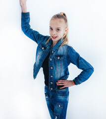 Young girl in a denim suit stands barefoot on a white background