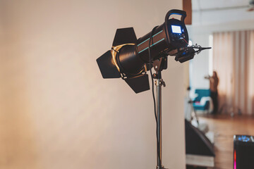 Studio lighting equipment radiates in anticipation as the videographer readies the set for a...