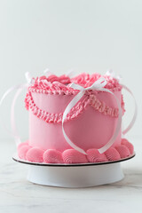 Delicate lambeth style birthday cake with pink cream cheese frosting decorated with cream tracery and happy birthday text on top. White background
