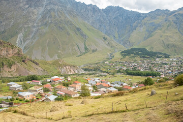 Picturesque mountain village nestled in valley surrounded by rugged peaks and green fields in...