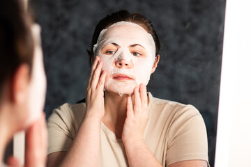Young adult practicing skincare with popular sheet mask. Ideal for Gen Z beauty trends or skincare education. Beauty and skincare concept.
