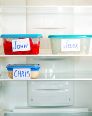 Meal containers labeled with employee names in clean office refrigerator. Lunch time for office...