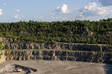 Open-Pit Quarry with Rock Layers and Green Forest Background