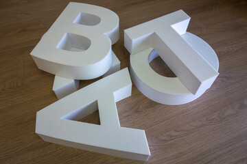 White three-dimensional letters made of plastic for the store's logo.Production of outdoor advertising in production.