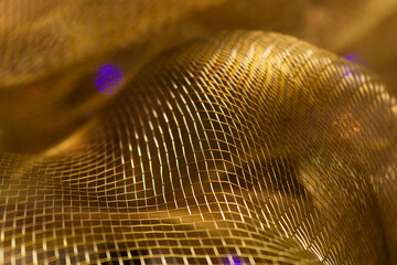 Golden Metallic Mesh with Purple Light Accents – Abstract Close-Up of Wavy Net Structure and...