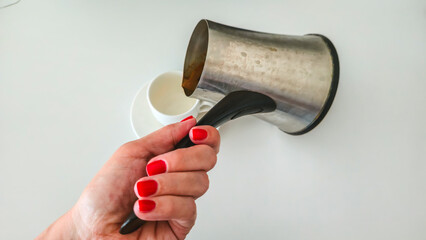 Pouring Turkish coffee into cup