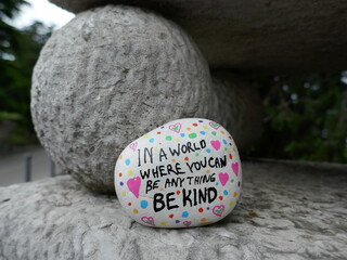 Supporting stone ball in statue with be kind kindness rock