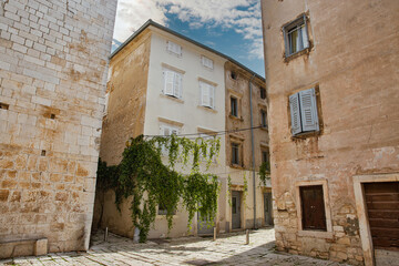 Naklejka premium Picturesque narrow street with green plants in Porec, Croatia.