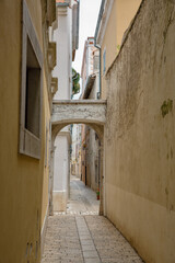Narrow stone alley with arch. Old European town Porec, Croatia.