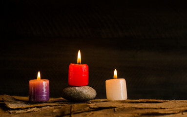 Velas encendidas de colores sobre superficie de madera y piedra en ambiente cálido y relajante