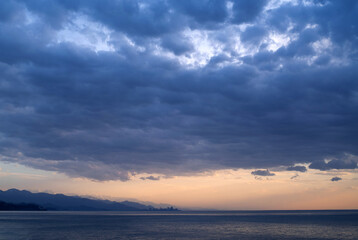 Fototapeta premium Sea blue cloudy before rain evening landscape. Black sea, sky, mountains and Batumi city are visible on the horizon, Georgia, Adjara