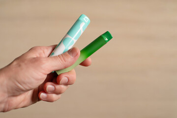 Various disposable electronic cigarettes in a female hand on a light background