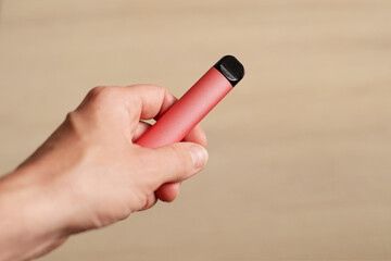 Disposable electronic cigarette in a female hand on a light background
