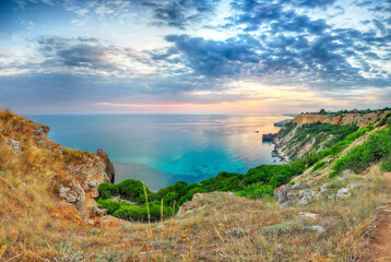 Unbelivable sunset at cape Fiolent with bushes grass and rocks at foreground.