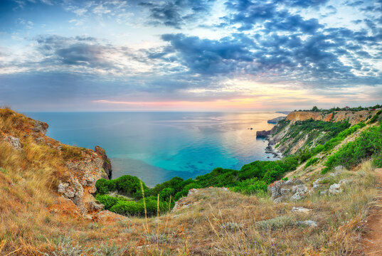 Unbelivable sunset at cape Fiolent with bushes grass and rocks at foreground.