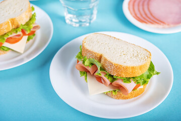 Sandwich with ham, cheese and lettuce on a blue background