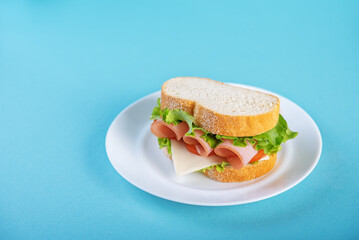 Sandwich with ham, cheese and lettuce on a blue background