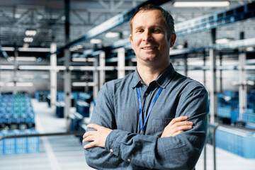 Portrait of smiling data center engineer analyzing infrastructure performance, configuring server...
