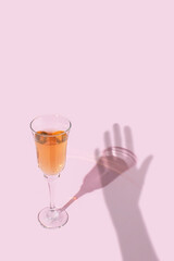 Wine glass and hand shadow on bright pink background. Creative concept.