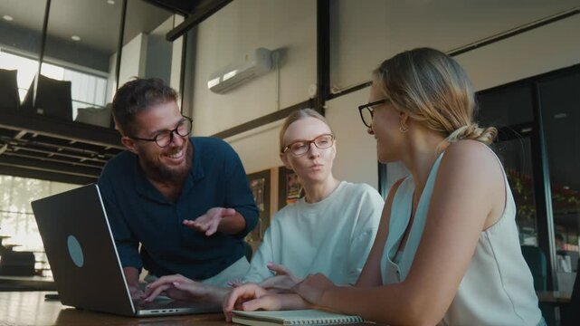 Three colleagues brainstorming discussing a project, collaborating around laptop in modern office environment, sharing ideas and working together. Office brainstorming to obtain highest productivity - Powered by Adobe