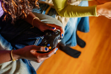 Two women enjoying quality time together, playing video games on a cozy date night at home, sharing...