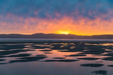 Sunset at low tide in Drakes Beach, Point Reyes, California, USA. The sun reflects off the water...