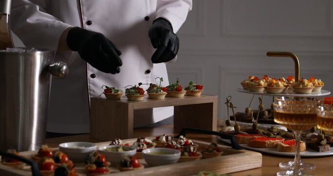 Chef arranging appetizers for buffet at table, closeup