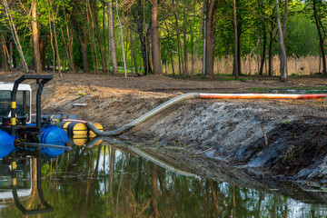 Hydraulic Dredge Pumping Water from a Pond with Reflection in a Forest