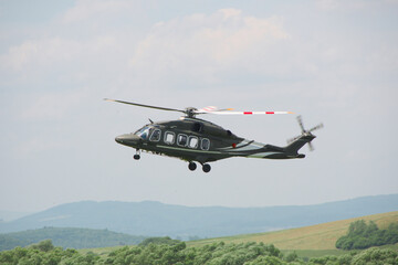 military transport helicopter with its landing gear down hovered over the ground as it approaches for landing